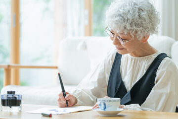 リビングで手紙を書くシニア女性